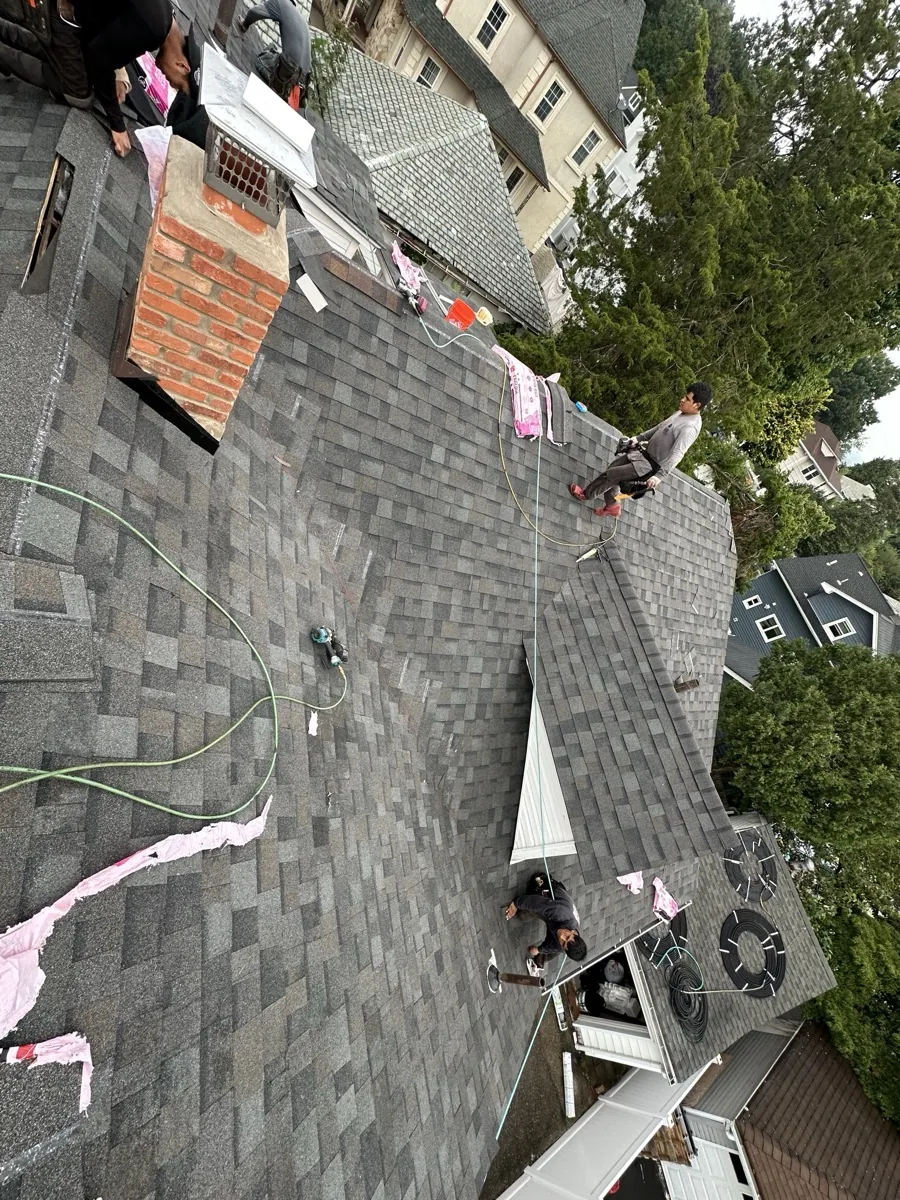 Crew repairing a brick chimney at the roofline in Clifton NJ